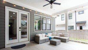 A covered patio with wicker furniture, a ceiling fan, and a view of a neighboring house.