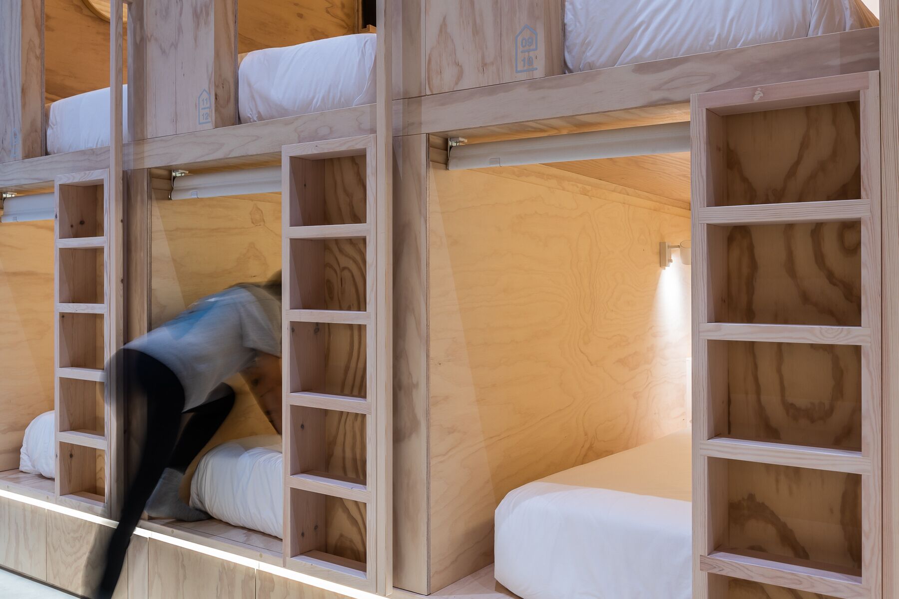 A bunk bed with wooden frames and white bedding.