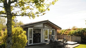 Et moderne hus med en patio, et spiseområde og en glasdør, der fører ind.