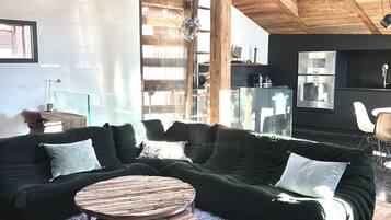 Ein modernes Wohnzimmer mit einem Ecksofa, einem runden Holztisch und einem flauschigen Teppich.