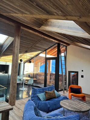 Um interior moderno com teto de madeira, um sofá azul e uma área de jantar com mesa e cadeiras.