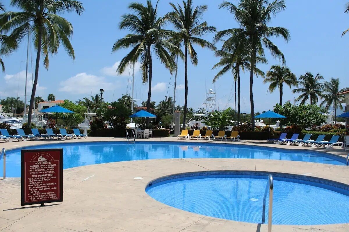 Una piscina con sillas de descanso y palmeras.