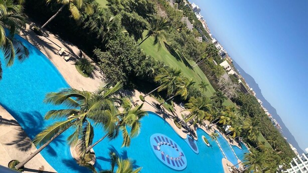 A resort with a large swimming pool surrounded by palm trees and a golf course. - CONDO BAL BY TRVL2HM (Nuevo Nayarit)
