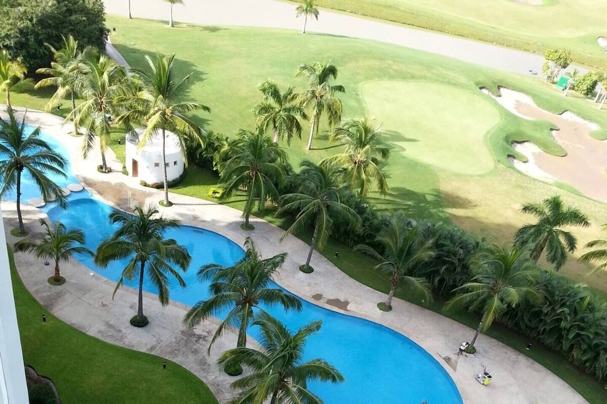 Um resort com piscina, palmeiras e campo de golfe.