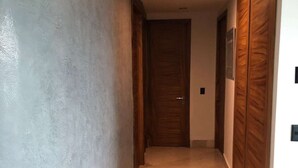 A hallway with a textured wall, a wooden door, and a tiled floor. - CONDO BAL BY TRVL2HM (Nuevo Nayarit)