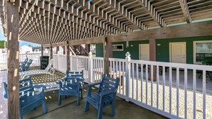A covered outdoor seating area with wooden benches and a pergola structure. - Beach Bunker by Silver Sands Vacation Rentals (Port Aransas)