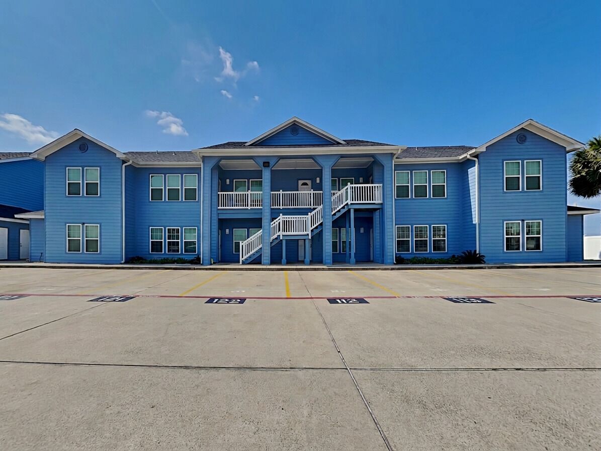 A multi-story building with a central staircase, large windows, and a flat roof.