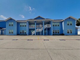 A multi-story building with a central staircase, large windows, and a flat roof.
