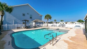 A swimming pool with a white fence, lounge chairs, and a palm tree. - Beach Bunker by Silver Sands Vacation Rentals (Port Aransas)