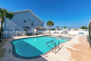 A swimming pool with a white fence, lounge chairs, and a palm tree. - Beach Bunker by Silver Sands Vacation Rentals (Port Aransas)
