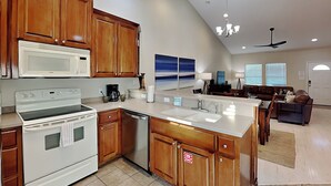 A modern kitchen with wooden cabinets, a white stove, and a dishwasher. - Beach Bunker by Silver Sands Vacation Rentals (Port Aransas)