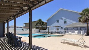 A covered outdoor swimming pool area with lounge chairs and a wooden deck. - Beach Bunker by Silver Sands Vacation Rentals (Port Aransas)