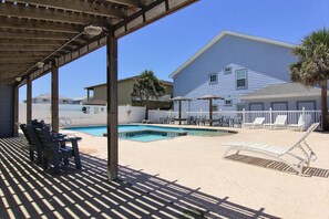 A covered outdoor swimming pool area with lounge chairs and a wooden deck. - Beach Bunker by Silver Sands Vacation Rentals (Port Aransas)