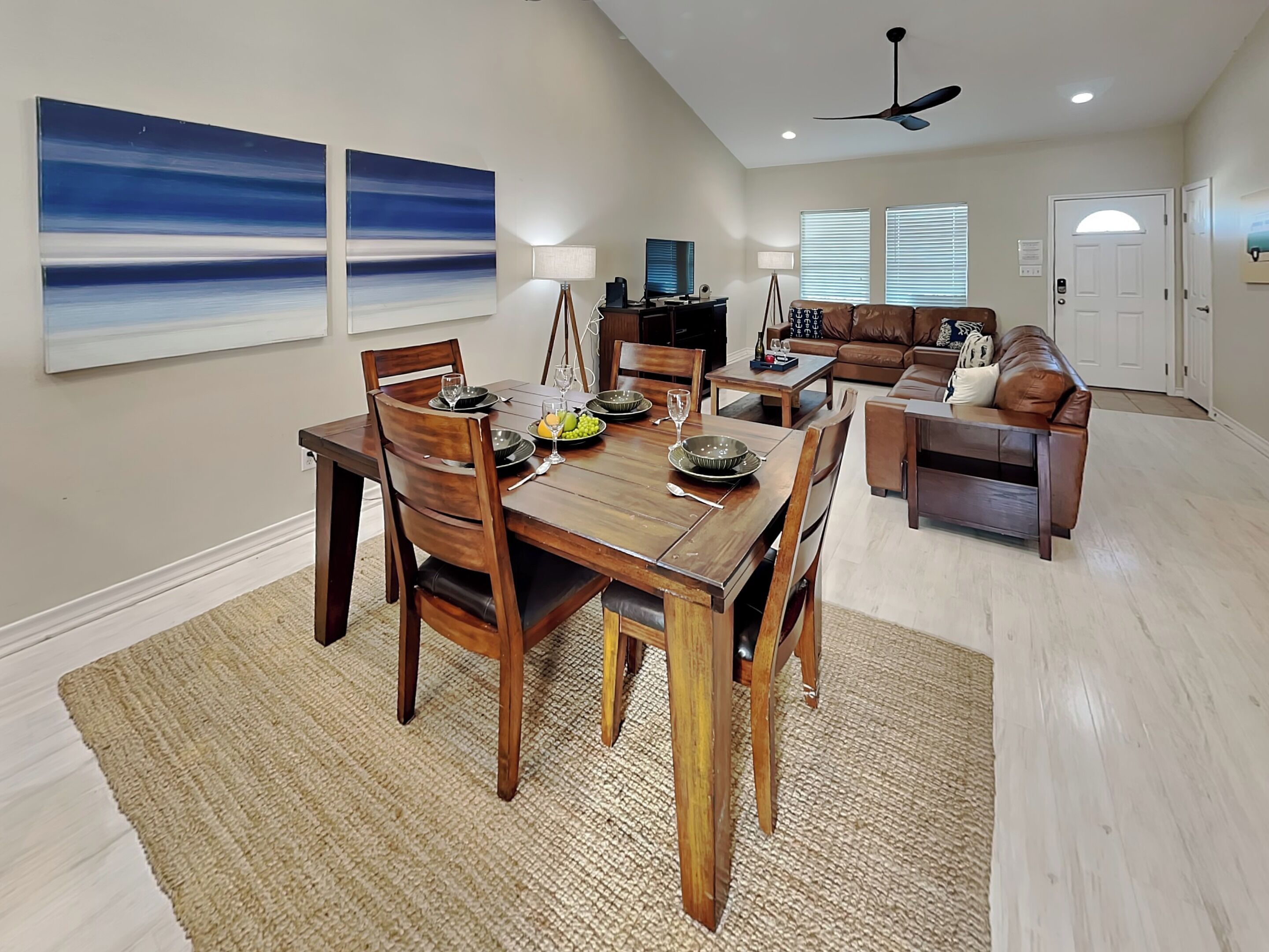 A dining area with a wooden table and chairs, a coffee table, and a sofa in the background.