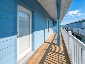 A wooden deck with a railing, a covered area with a ceiling, and a clear sky.