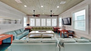 A spacious living room with a large sectional sofa, a coffee table, and a flat-screen TV mounted on the wall. - Beach Club 2 by Silver Sands Vacation Rentals (Port Aransas)