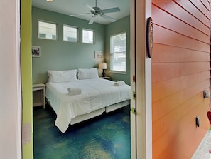 A bedroom with a bed, a nightstand, a lamp, and a ceiling fan. - Beach Club 2 by Silver Sands Vacation Rentals (Port Aransas)