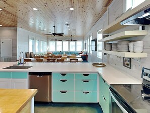 A modern kitchen with a central island, built-in appliances, and a dining area with chairs and tables. - Beach Club 1 by Silver Sands Vacation Rentals (Port Aransas)