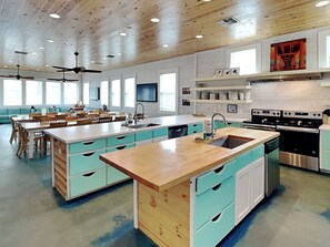 A spacious kitchen with a central island, built-in appliances, and a dining area with a sofa and chairs. - Beach Club 1 by Silver Sands Vacation Rentals (Port Aransas)