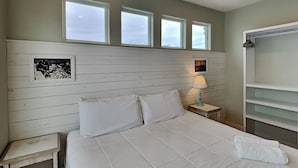 A neatly made bed in a room with a wooden headboard, a bedside table with a lamp, and a wardrobe. - Beach Club 1 by Silver Sands Vacation Rentals (Port Aransas)
