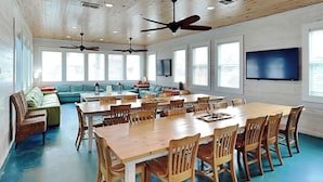 A spacious room with a large wooden table and chairs, a sofa set, and ceiling fans. - Beach Club 1 by Silver Sands Vacation Rentals (Port Aransas)