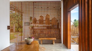 A wooden bench and a table in a hallway with a wooden lattice partition. - Mikiki Lifestyle Hotel (Cajueiro da Praia)