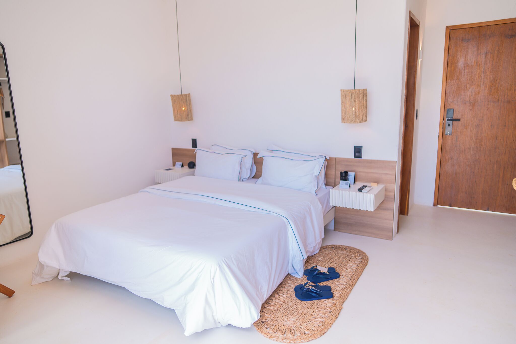 A bedroom with a large bed, bedside tables, a wooden door, and a mirror.