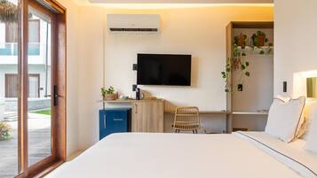 Habitación de hotel con cama, escritorio, silla, televisión, minibar y ventana con vistas al exterior.