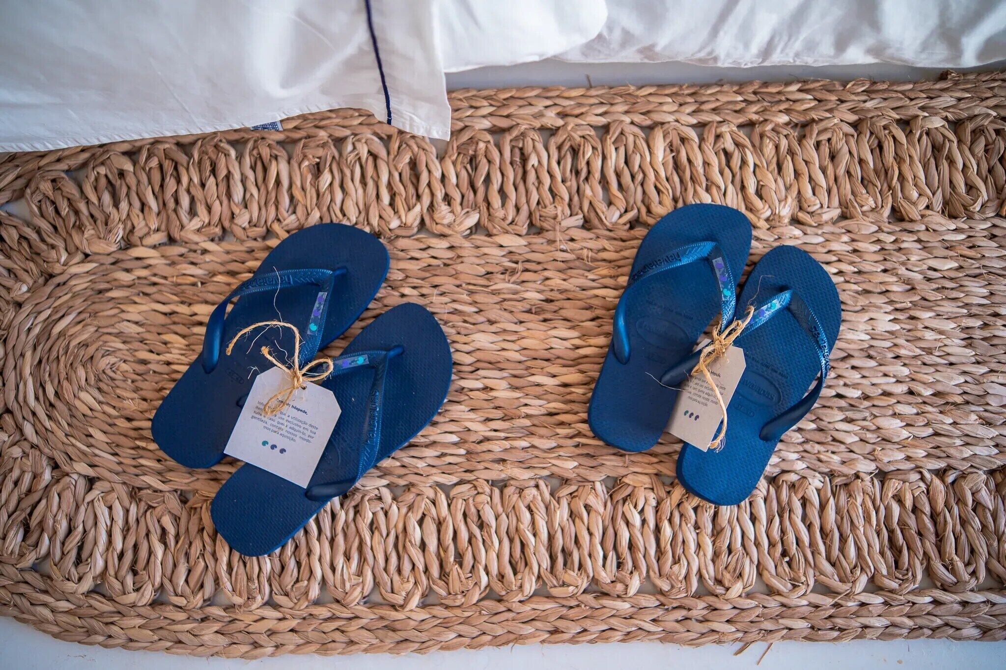 A woven mat with two pairs of blue flip-flops placed on it.
