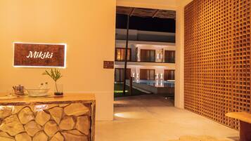 A reception area with a stone wall, a sign reading "Miki", a reception desk, and a view of a pool area.