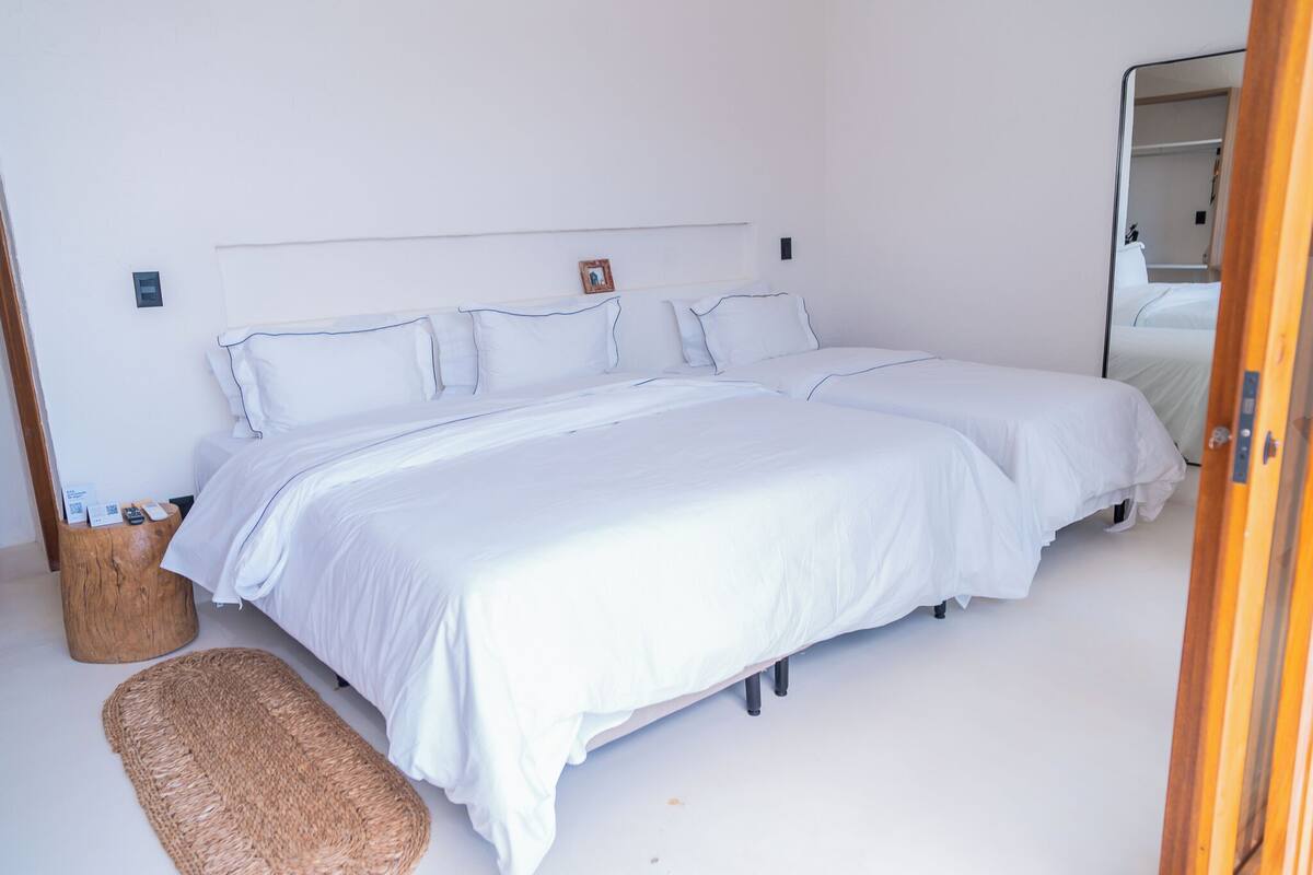 A double bed with white bedding, a bedside table with a lamp, and a woven rug on the floor.