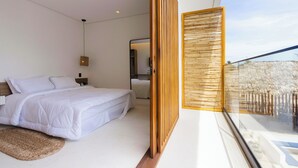 A modern bedroom with a large bed, a bedside table, a hanging light, and a view of a balcony with a wooden railing. - Mikiki Lifestyle Hotel (Cajueiro da Praia)