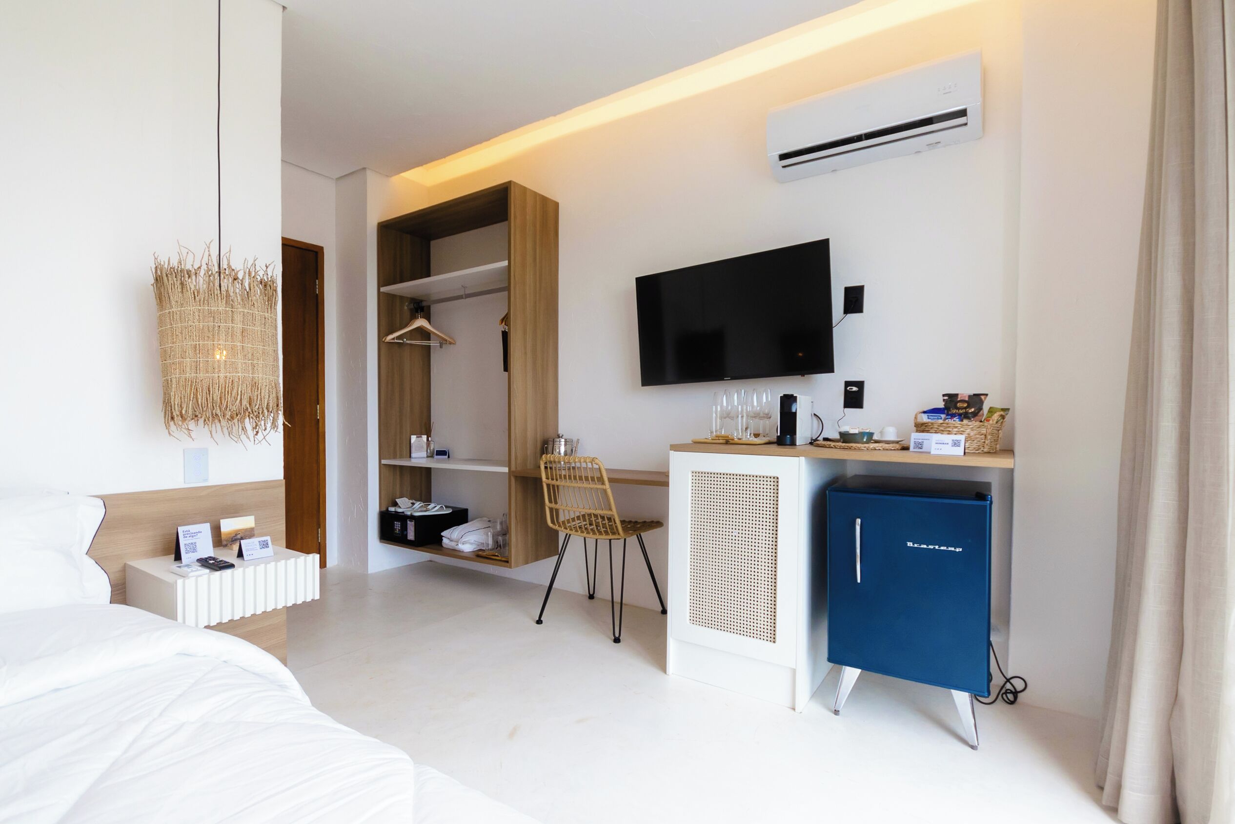 A modern hotel room with a bed, a desk with a computer, a TV, and a wardrobe.