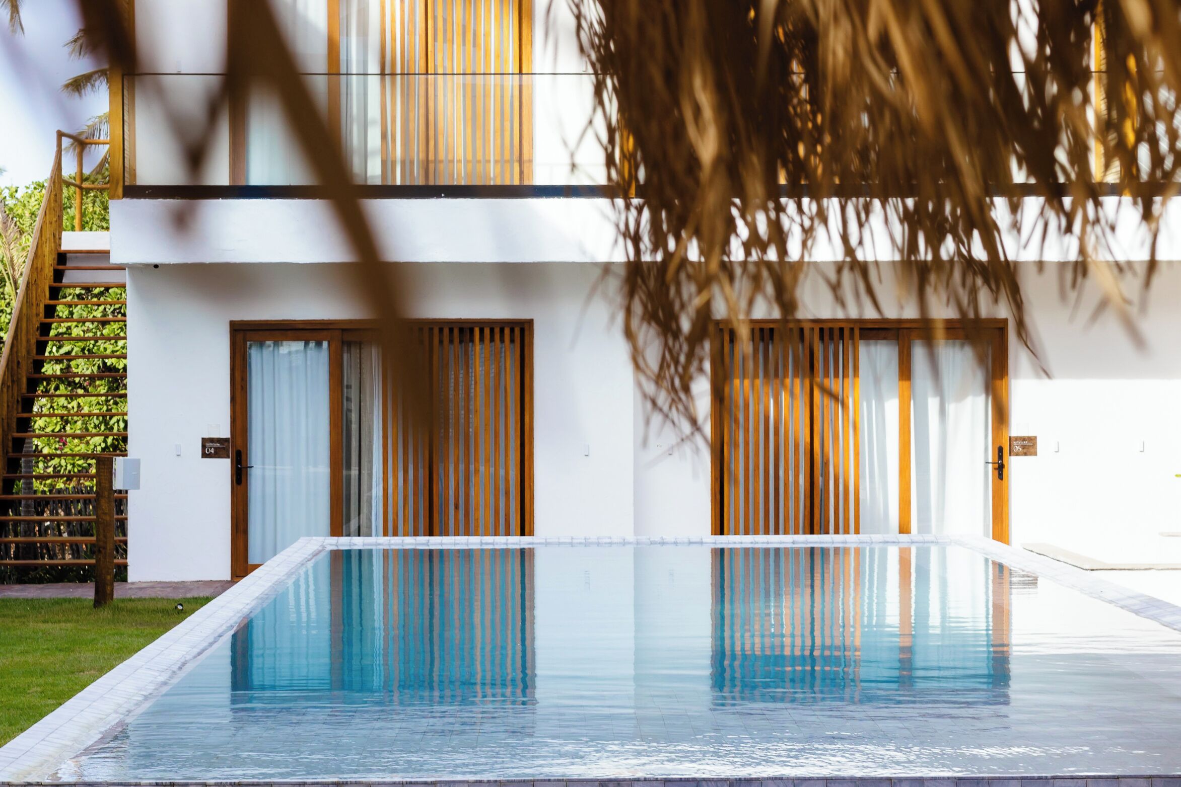 Un edificio moderno con piscina, puertas de madera y una escalera.