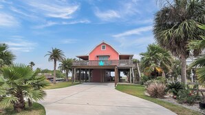 A two-story house with a red exterior and a balcony. - Beachin' Country by Silver Sands Vacation Rentals (Port Aransas)