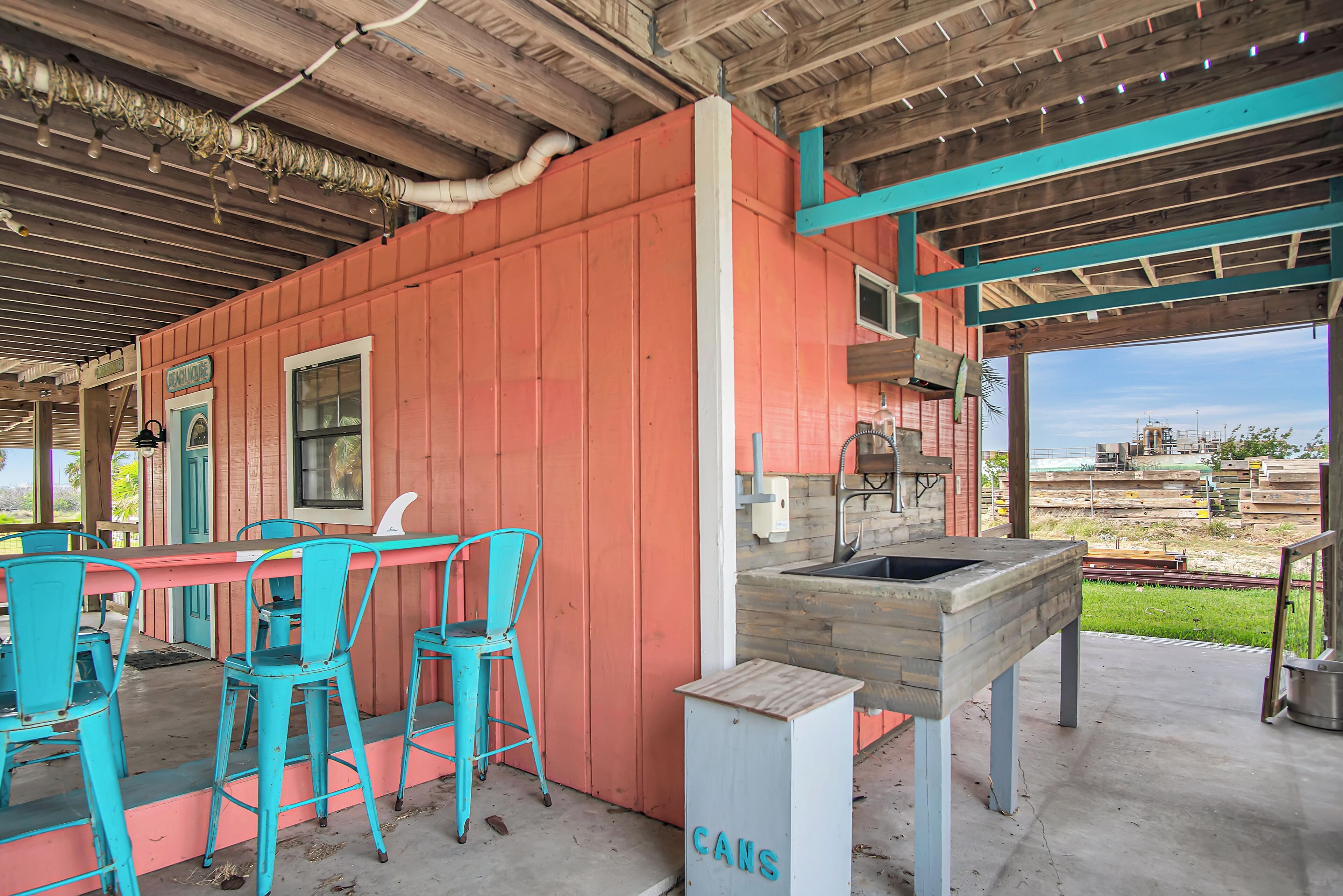 Un coin bar au style rustique, avec des chaises turquoise, un comptoir en bois et un panneau indiquant « BOÎTES DE CONSERVE ».