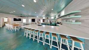Een ruime keuken met een groot eiland, barstoelen en een eethoek met stoelen.