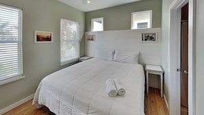 Een slaapkamer met een groot bed, twee nachtkastjes, een hoofdeinde en een deur.
