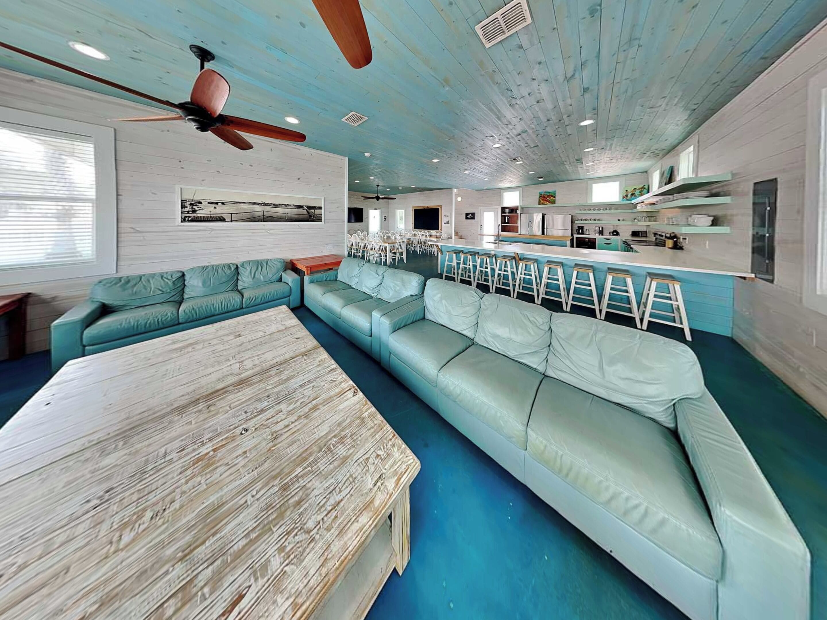 A spacious living area with a large L-shaped sofa, a wooden coffee table, and a ceiling fan.