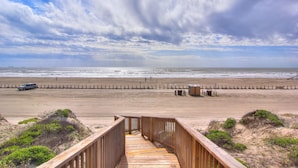 A wooden boardwalk leading to a beach with a sandy shoreline and a cloudy sky. - Bella Vista by Silver Sands Vacation Rentals (Port Aransas)