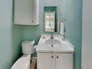 A bathroom with a toilet, sink, and cabinet.