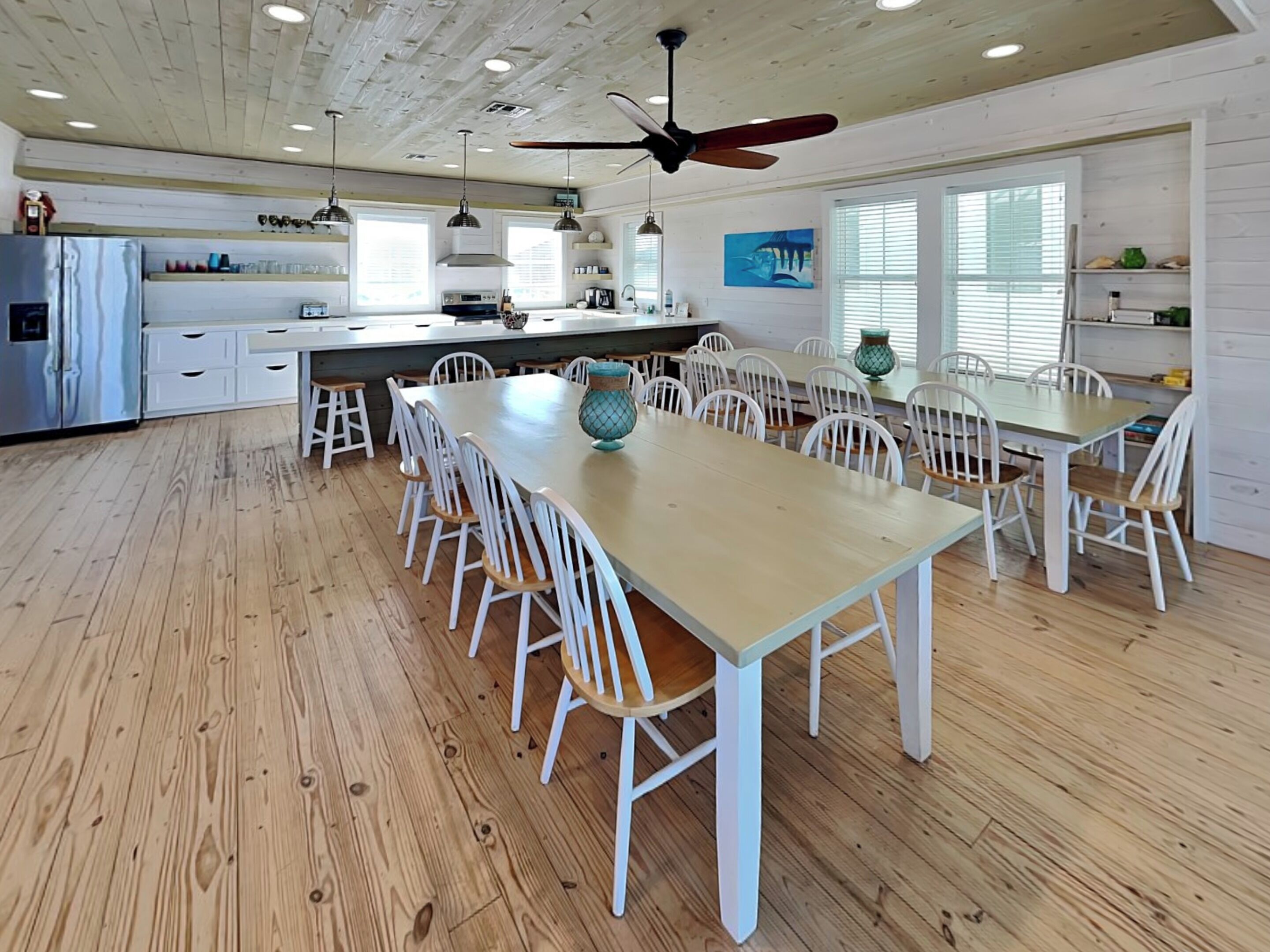 Une cuisine spacieuse dotée d’un grand îlot central, de meubles blancs et d’un plancher en bois.