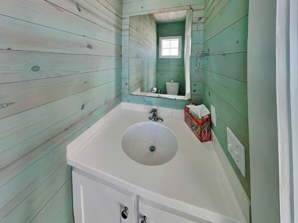 A bathroom with a white sink, a mirror, and a window.