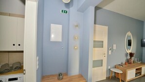 A hotel room with a wooden desk, a mirror, a small plant, and a washing machine.