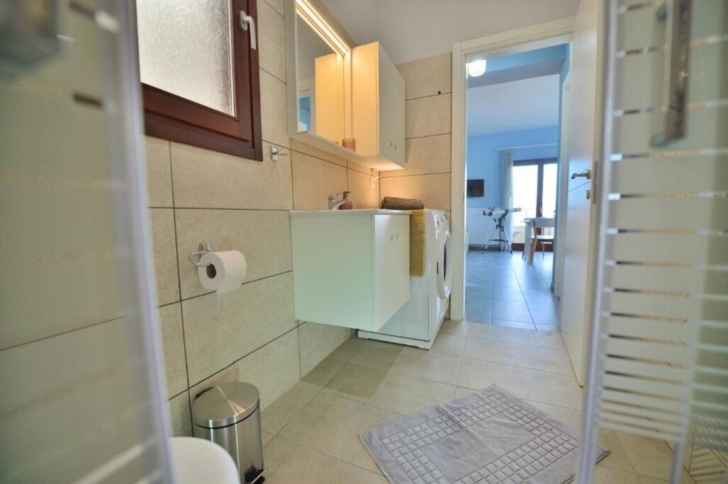 A compact bathroom with a toilet, a trash bin, a towel, and a mirror.