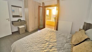 A bedroom with a bed, a wardrobe, a bedside table, and a window with a view of the outside.