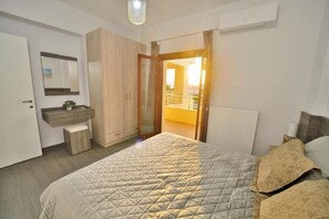 Quarto com cama, guarda-roupa, mesa de cabeceira e janela com vista para o exterior.