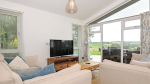 A modern living room with a flat-screen TV, beige sofas, and a wooden coffee table. - 8 Horizon View (Liskeard)