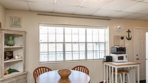 A compact kitchen with a dining table, chairs, a microwave, and a small refrigerator. - Buried Treasure by Silver Sands Vacation Rentals (Port Aransas)