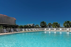 A swimming pool with lounge chairs and a building with a red roof.